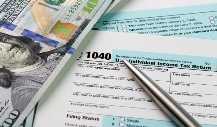 Filling out income tax forms with US dollar and pen